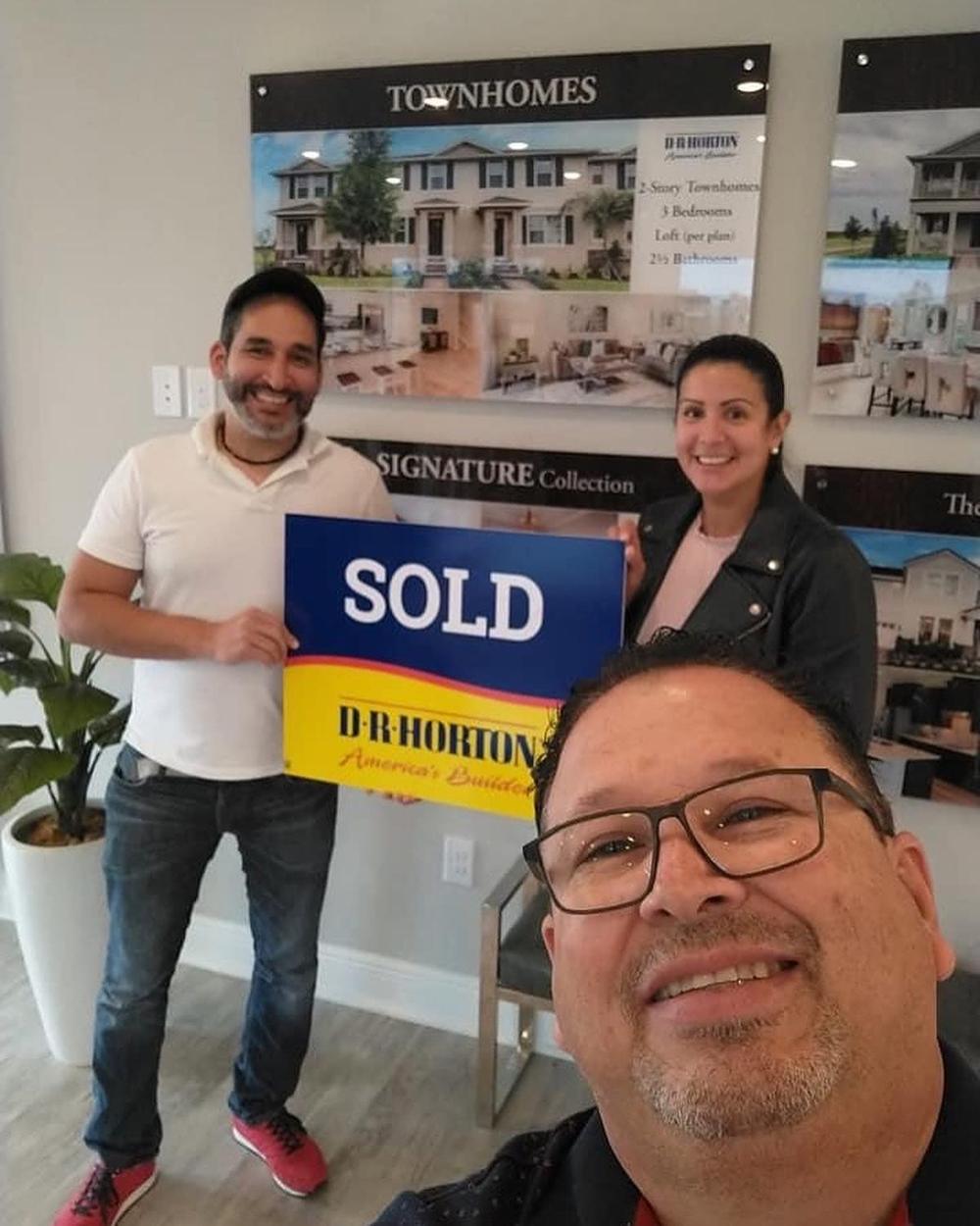 Buyers with the sold sign at their new construction home